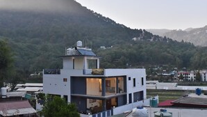 A modern building with a sign reading "Nashville" on a hilltop, surrounded by greenery and other buildings. - Nakshville  (Bhimtal)