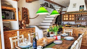 A dining area with a wooden table set for a meal, a wine bottle, and a vase with flowers. - Terrazzo Prato Pernice Apt.12 by Interhome (Orselina)