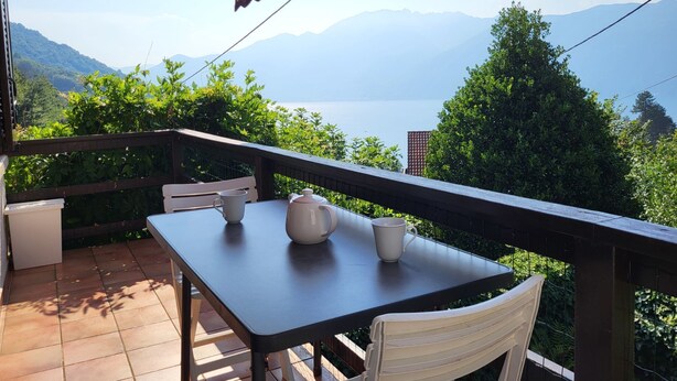 A balcony with a table and chairs, overlooking a mountainous landscape and a body of water. - La Gioconda by Interhome (Vairano)