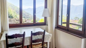 A dining table with a white tablecloth and wooden chairs, positioned by large windows with a mountain view. - La Gioconda by Interhome (Vairano)