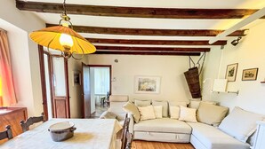 A cozy living room with a wooden floor, a white sofa, and a dining table with a bowl on it. - La Gioconda by Interhome (Vairano)
