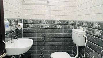 A small bathroom with a toilet, sink, and shower.