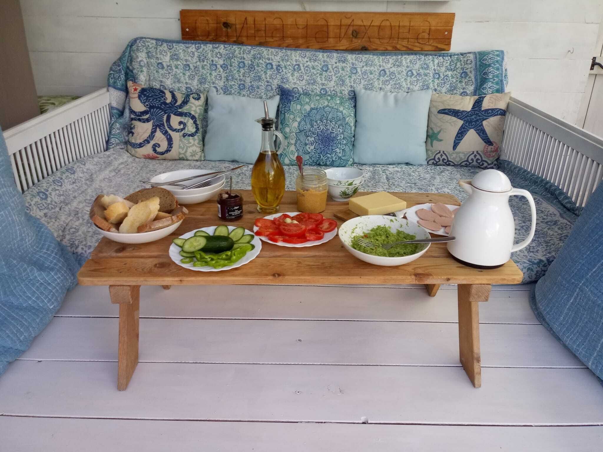 A wooden table with food items and a white pitcher on a white wooden floor.