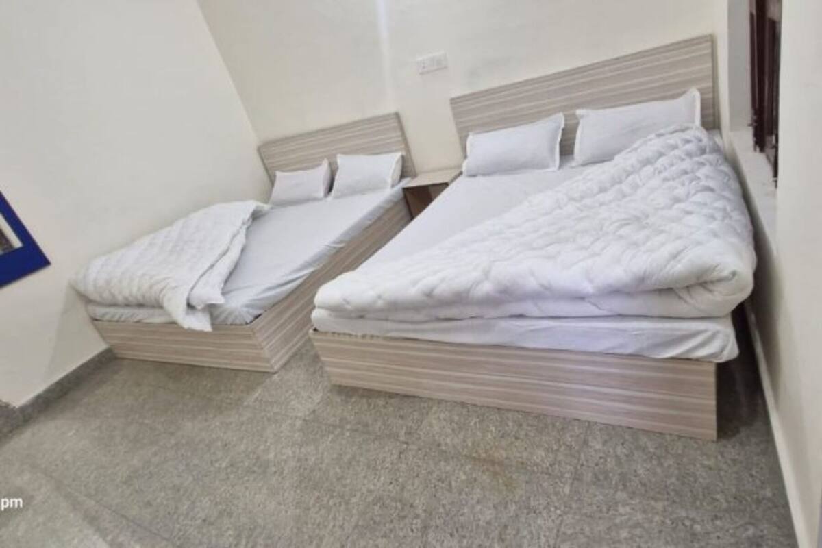 A room with two beds, each with a wooden headboard and white bedding.