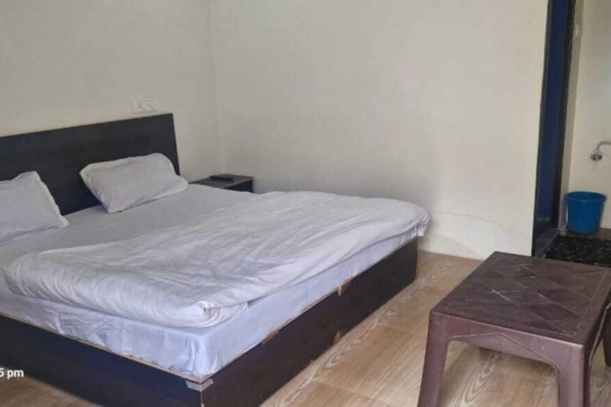 A single bed with a wooden headboard, a small bedside table, and a nightstand.