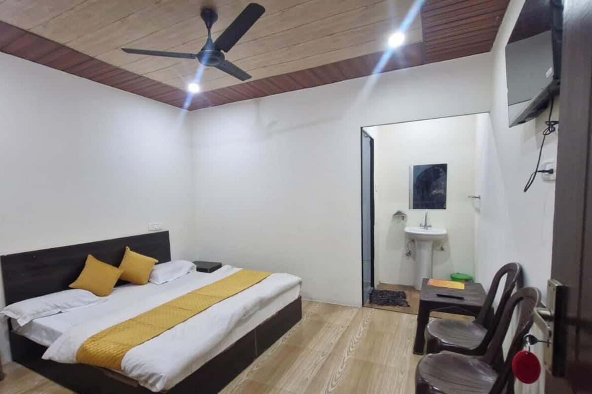 A bedroom with a bed, a ceiling fan, a bedside table, a chair, and a mirror.