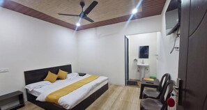 A bedroom with a bed, a ceiling fan, a bedside table, a chair, and a mirror.