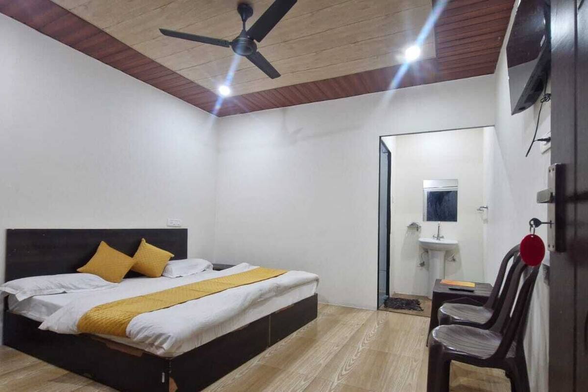 A bedroom with a bed, a ceiling fan, a bedside table, a chair, and a wardrobe.