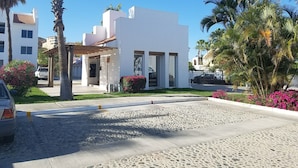 A modern building with a white facade, large windows, and a covered outdoor area. - Contemporary Conveniently Located 1 BR condo, Walk to beach, restaurants & bars. (San José del Cabo)