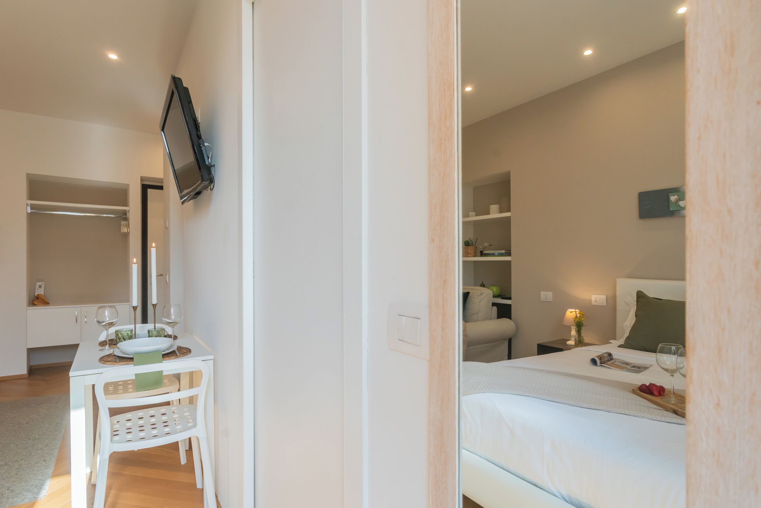 A bedroom with a bed, bedside table, and a TV mounted on the wall.