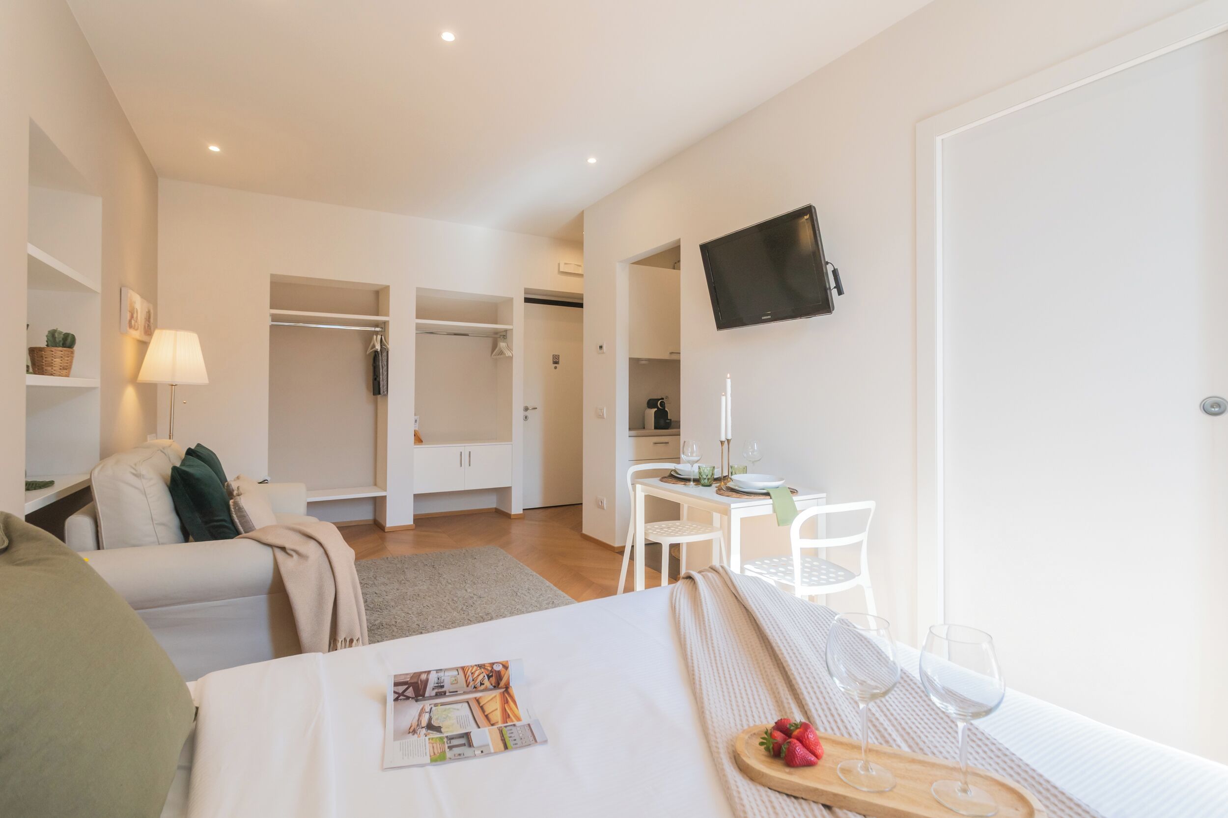 Ein modernes Hotelzimmer mit Bett, einer kleinen Essecke, einem Fernseher und einem Kleiderschrank.