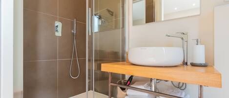 Une salle de bain moderne avec une douche à parois de verre, un lavabo blanc et un meuble-lavabo en bois.