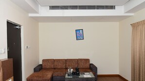 Een moderne woonkamer met een hoekbank, een glazen salontafel en een kunstwerk in een lijst aan de muur.