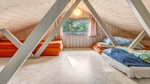 Une chambre mansardée chaleureuse avec deux lits, une fenêtre et une vue sur les arbres.
