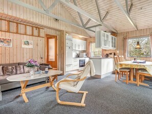 Un intérieur de chalet chaleureux comprenant un coin repas, une cuisine et un espace salon.