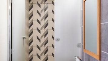 Un baño moderno con una pared estampada en patrón de chevron, un lavamanos blanco y un espejo con marco de madera.