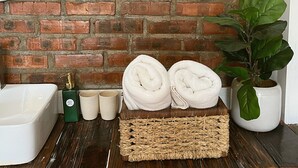 A bathroom with a white bathtub, a green soap dispenser, two beige cups, and a woven basket with towels. - D Home Sapa 2 (Sa Pa)