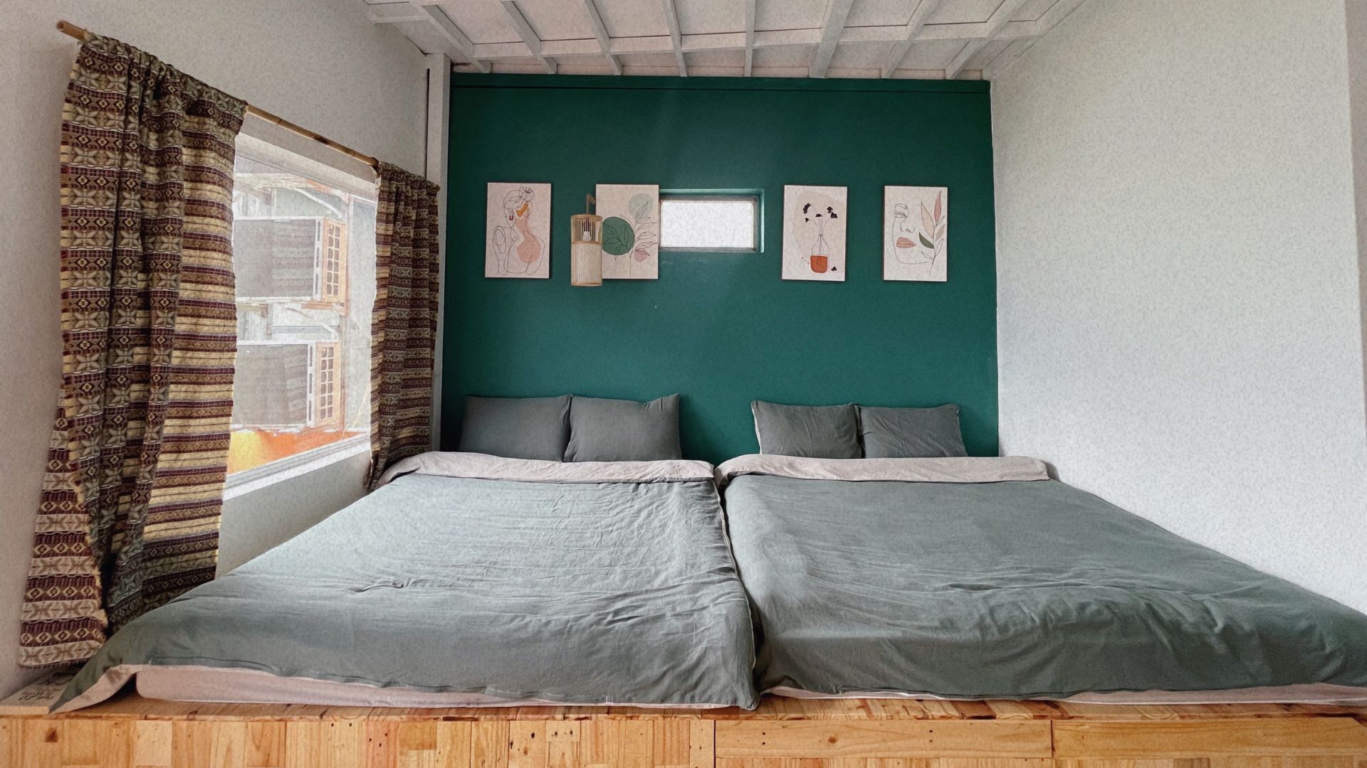 Una habitación con dos camas, una ventana con cortinas estampadas y decoración en la pared.