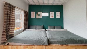 A room with two beds, a window with patterned curtains, and wall art. - D Home Sapa 2 (Sa Pa)