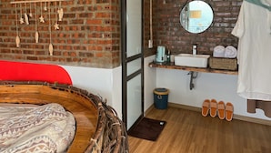 A cozy room with a brick wall, a wooden bed, a small white sink, and a mirror. - D Home Sapa 2 (Sa Pa)