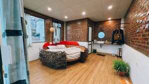 A bedroom with a stone headboard, a red bed, a brick wall, a wooden floor, a window with a view, and a small plant. - D Home Sapa 2 (Sa Pa)