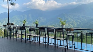 A terrace with chairs and potted plants, overlooking a mountainous landscape. - D Home Sapa 2 (Sa Pa)