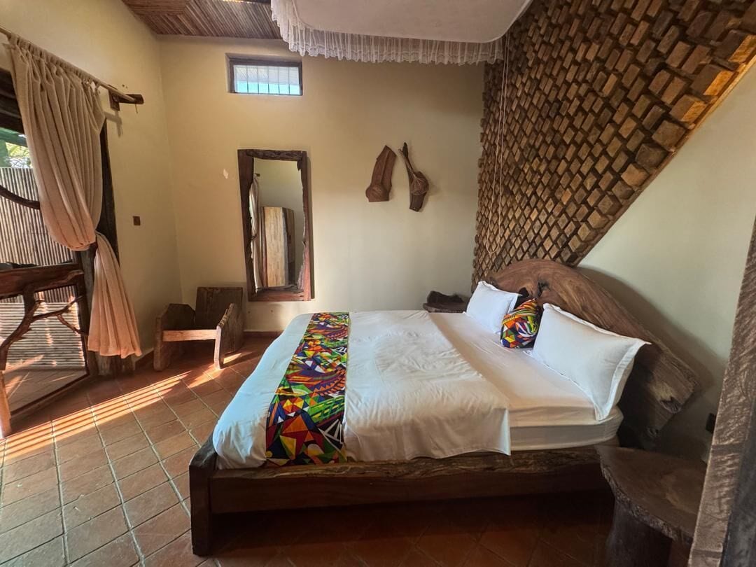 Une chambre à coucher avec un lit, une fenêtre, un miroir et une tête de lit en bois.