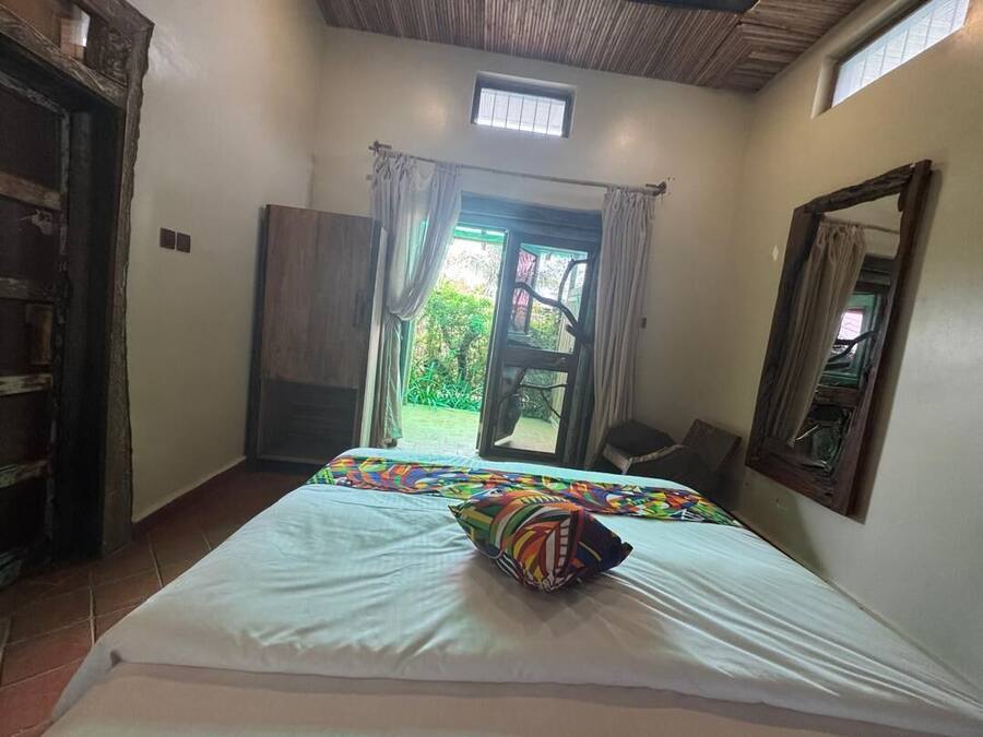 Une chambre à coucher avec un lit, une fenêtre avec des rideaux, une porte et une vue sur l’extérieur.
