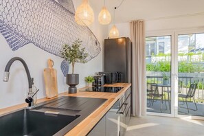 Una cocina moderna con estufa integrada, un fregadero y una zona de comedor con mesa y sillas.