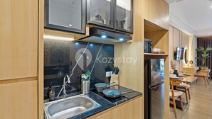 A modern kitchen with a stainless steel sink, a stove, and wooden cabinets. - Rivana by Kozystay - Nusa Dua (Nusa Dua)