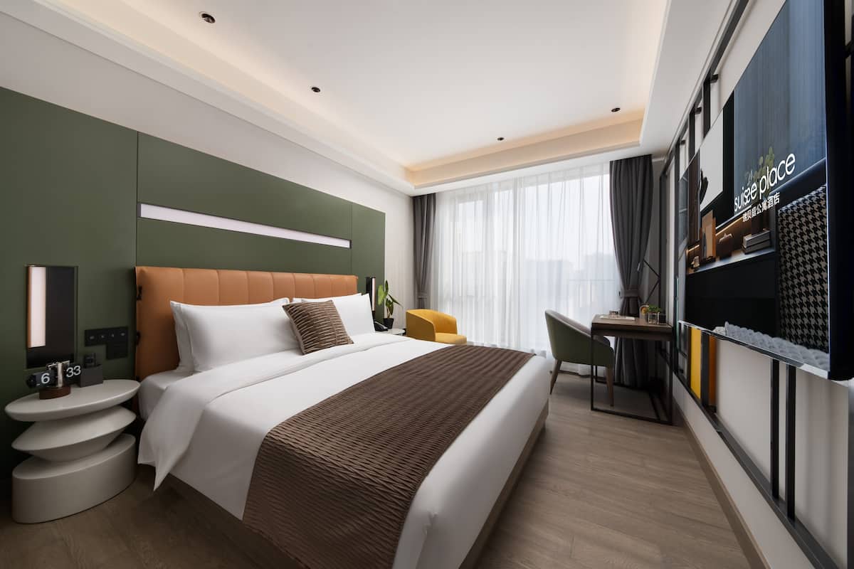 A modern hotel room with a large bed, a desk, and a TV.