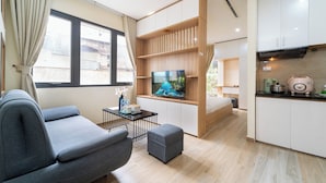 Ein modernes Wohnzimmer mit einer Couch, einem Fernseher, einem kleinen Tisch und einer Küchenzeile.