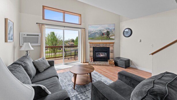 A living room with a fireplace, a sofa, a coffee table, and a view through a sliding glass door.