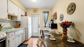 A compact kitchen with white cabinets, a stove, and a dining area with a wooden table and chairs.