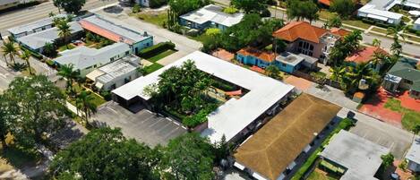 An aerial view of a residential area with various buildings, including a large rectangular structure with a flat roof and a smaller adjacent building with a sloped roof.