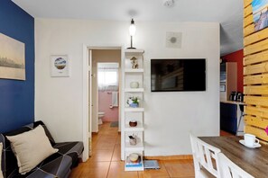 Una sala de estar con un sofá, una mesa de centro, un televisor y una estantería.