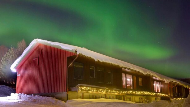 A wooden building with a snow-covered roof and a red section on the left.