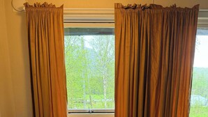 A room with a round table, two chairs, and a window with curtains.