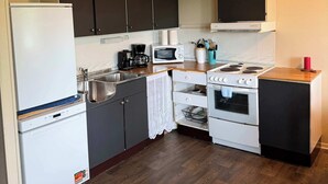 A compact kitchen with a refrigerator, microwave, coffee maker, stove, and cabinets.