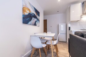 A modern kitchen with white cabinetry, a built-in oven, and a refrigerator. - Haymarket House (Basingstoke)