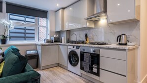 A compact kitchen with a built-in washer and dryer, a microwave, and a gas stove. - Haymarket House (Basingstoke)