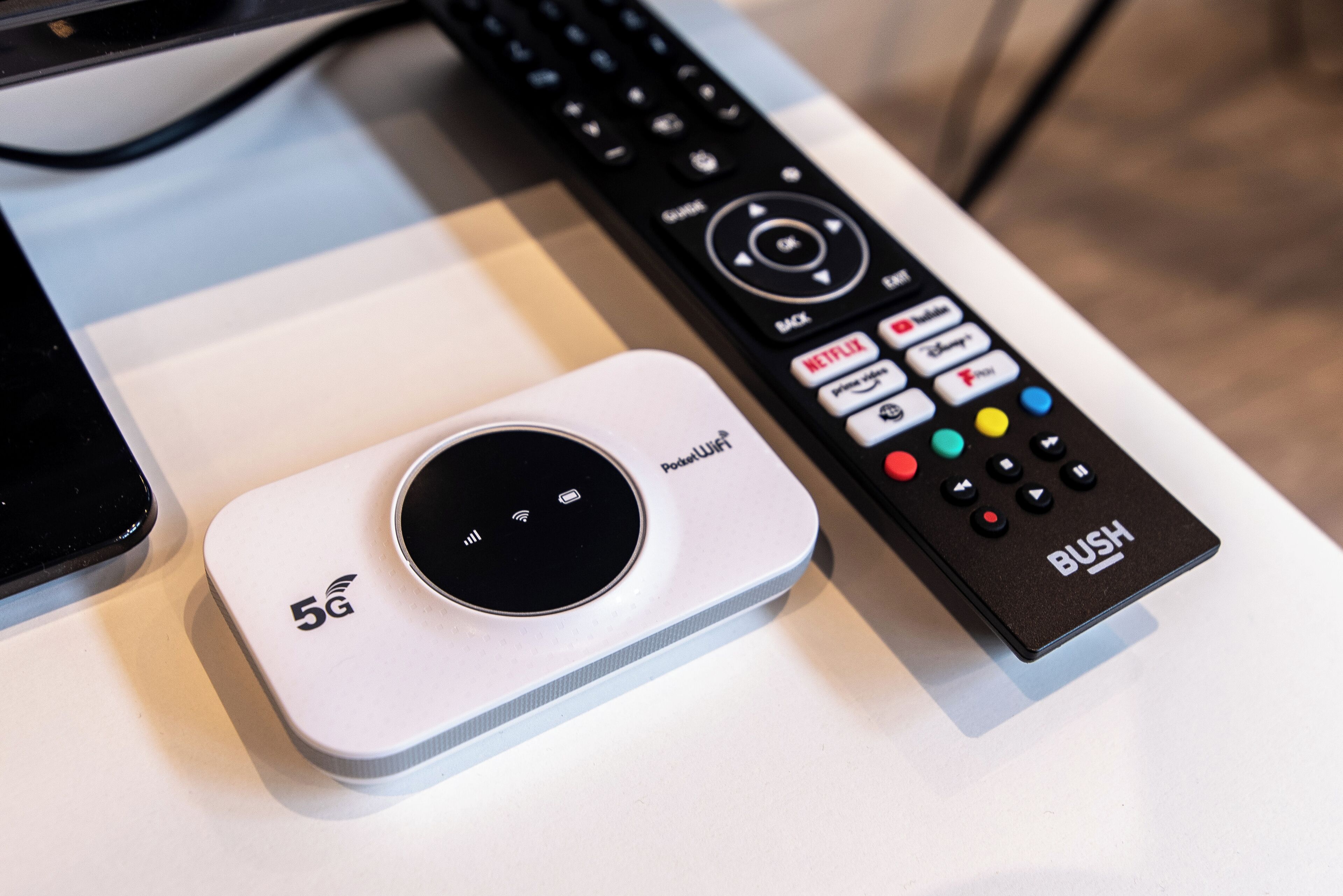 A 5G-enabled device and a remote control on a table.
