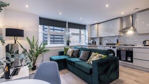 A modern kitchen with white cabinets, a built-in oven, and a stainless steel range hood. - Haymarket House (Basingstoke)