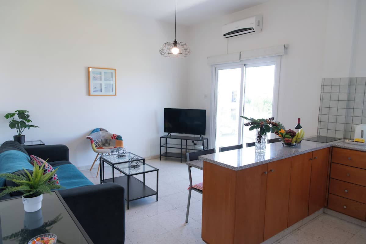 Una sala de estar moderna con sofá, televisión y zona de comedor.