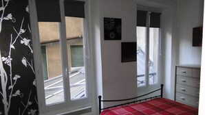 Une chambre à coucher avec un lit, une commode et deux fenêtres.