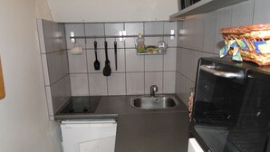 Une cuisine compacte équipée d’un four à micro-ondes, d’un évier et d’un petit réfrigérateur.