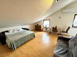 Una camera da letto con un letto, una scrivania e una sedia. Una finestra permette l'ingresso di luce naturale.