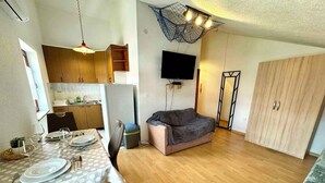 A compact living space with a dining area, kitchenette, and a sofa. - App Vida (Crikvenica)