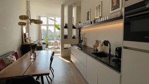 A modern kitchen with a dining area, large windows, and a view of the outdoors.