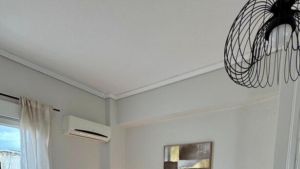 Et soveværelse med en seng, to sengeborde med lamper, en radiator og en loftsvifte.